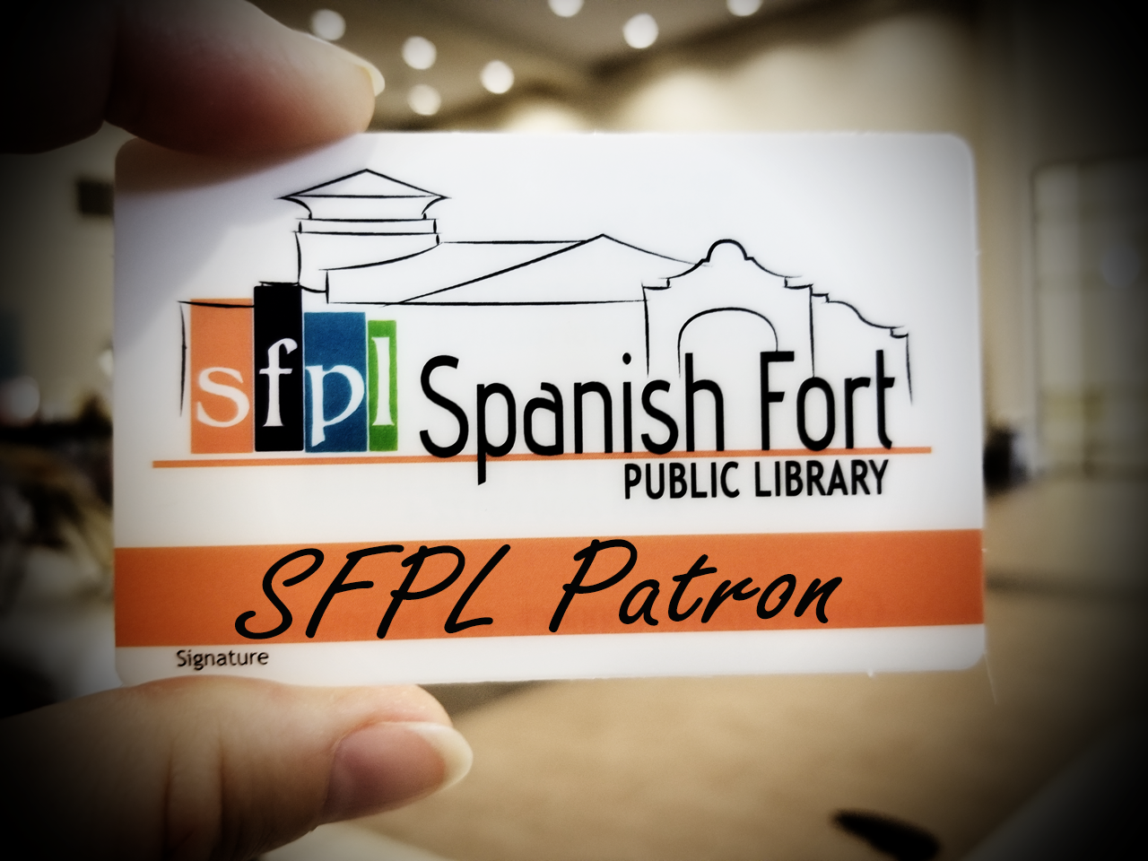 close-up photograph of a hand holding up a Spanish Fort Public Library patron card