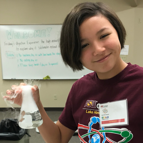 Girl holding beaker during STEM academy experiment