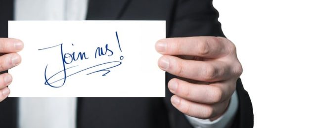 Picture of "Join Us" written on a notecard in sharpie held up by a well dressed man Picture of "Join Us" written on a notecard in sharpie held up by a well dressed man