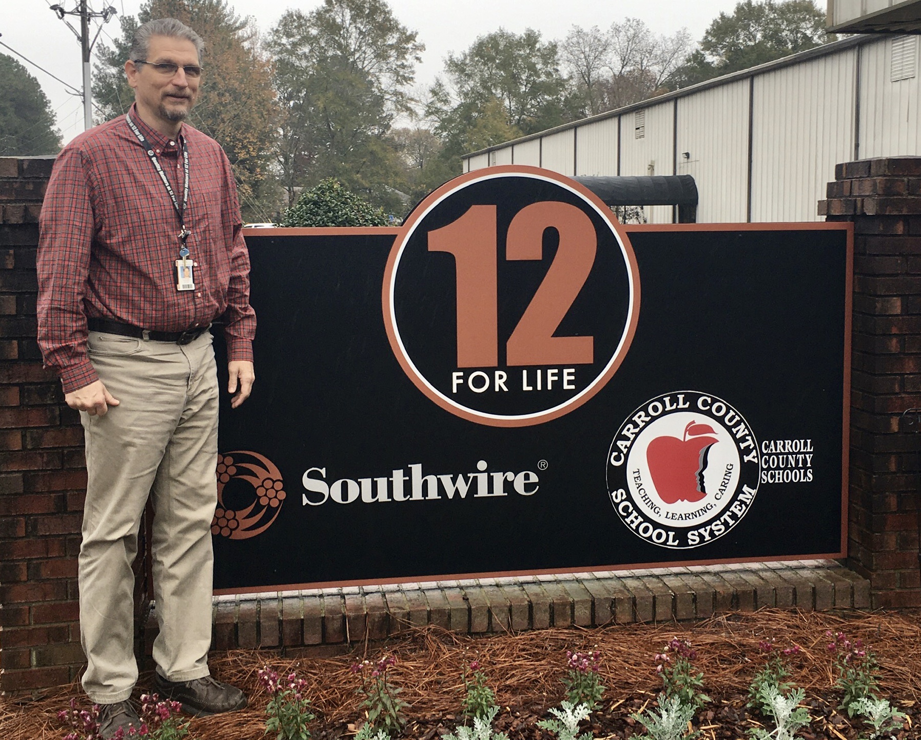 Joel Grubbs standing in front of the 12 for Life program sign outside the facility