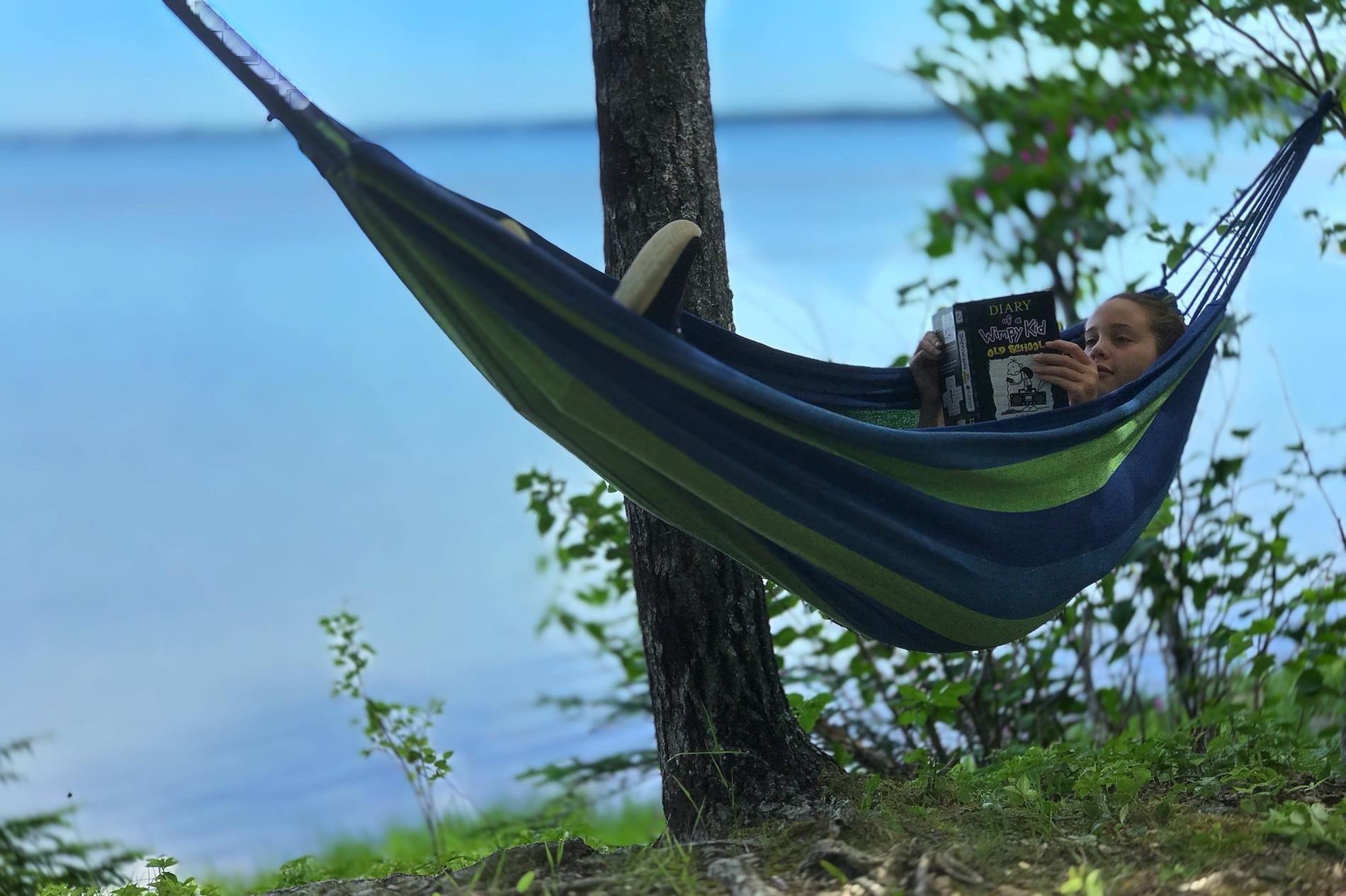 Kid reading in a hammock 