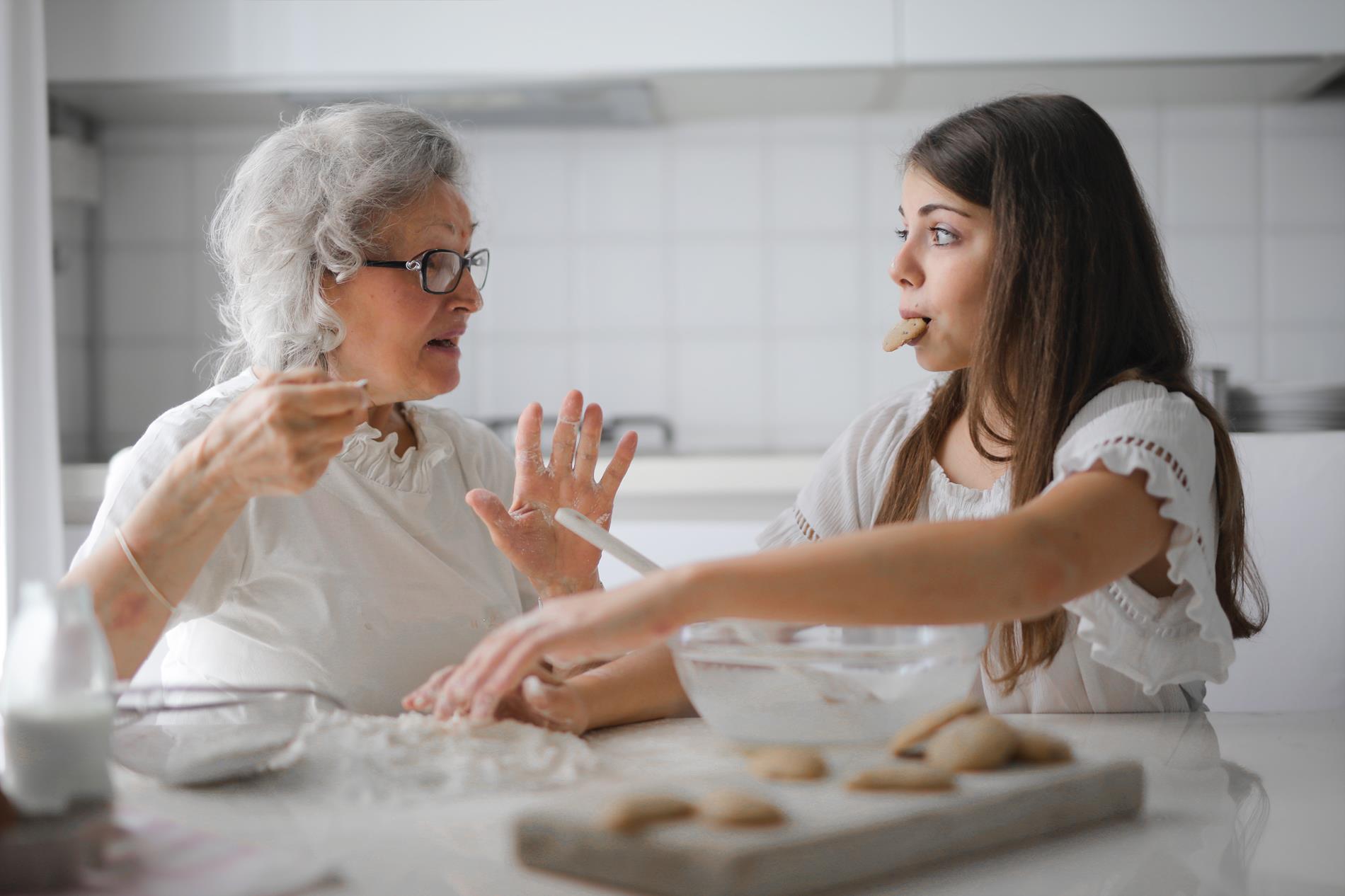 Grandmother teaching teenage granddaughter to bake cookies